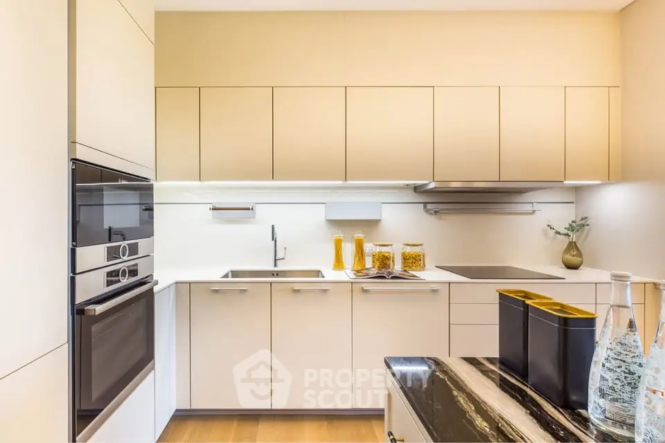 Modern kitchen with sleek cabinetry and built-in appliances, featuring a stylish black marble countertop.