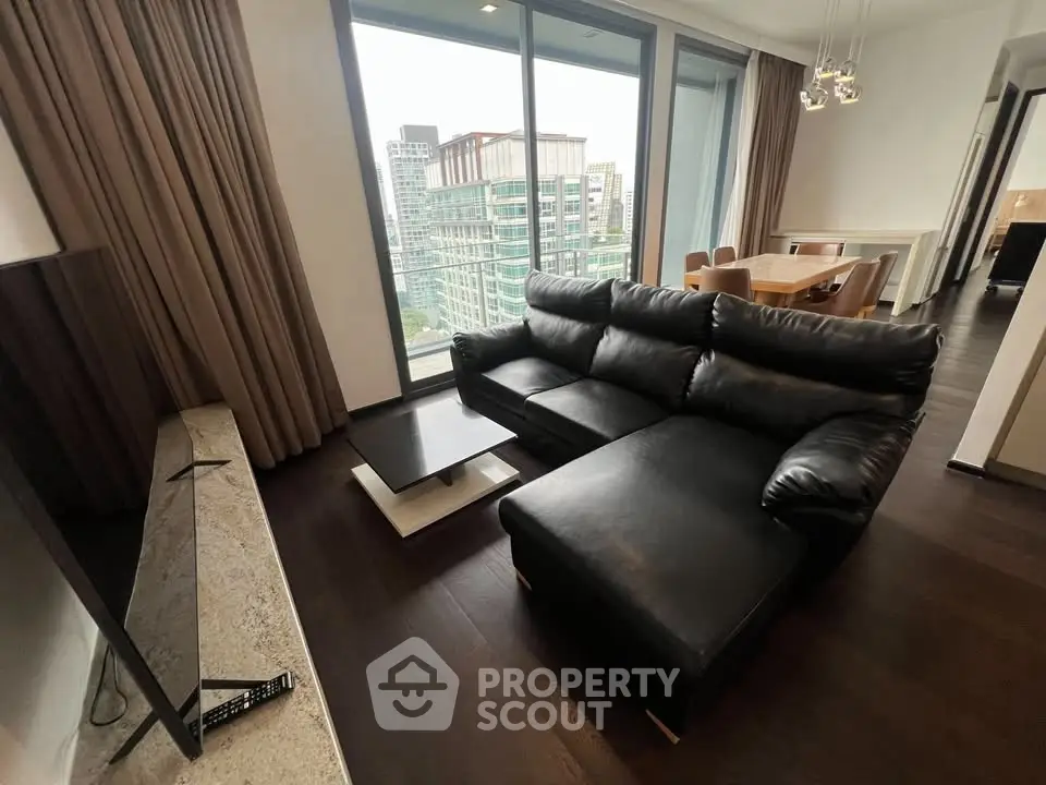 Luxurious living room with modern black leather sofa and city view from large windows.