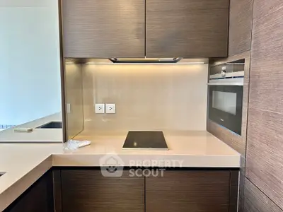 Modern kitchen with sleek cabinetry and built-in appliances, featuring an electric cooktop and oven.