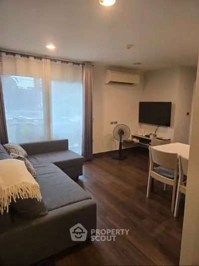 Cozy living room with modern decor, featuring a sectional sofa, wall-mounted TV, and dining area.