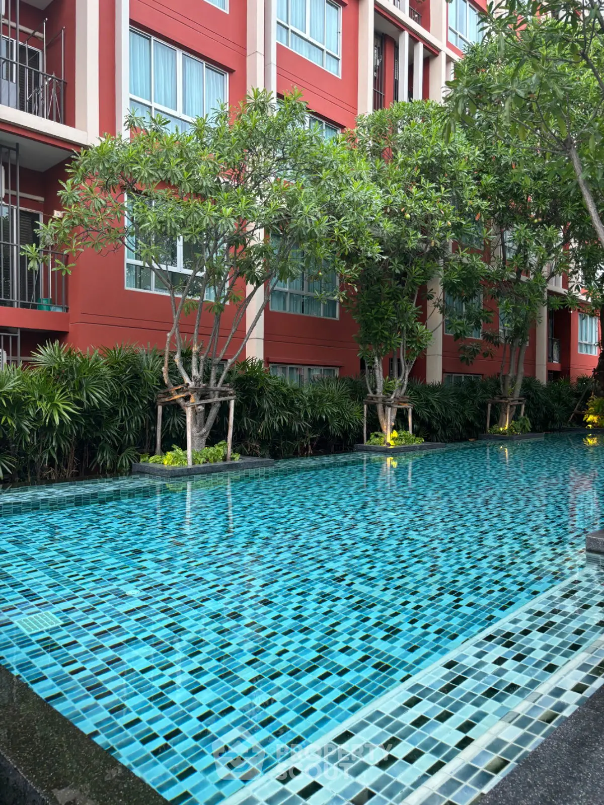 Luxurious apartment complex with stunning outdoor pool and lush greenery.