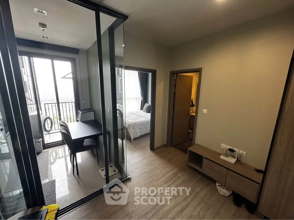 Modern apartment interior with glass partition, cozy bedroom, and balcony view.