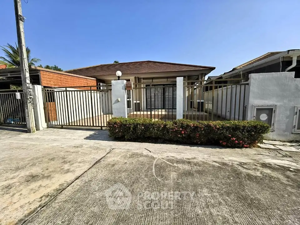 Charming single-story home with gated entrance and manicured hedge in a quiet neighborhood.