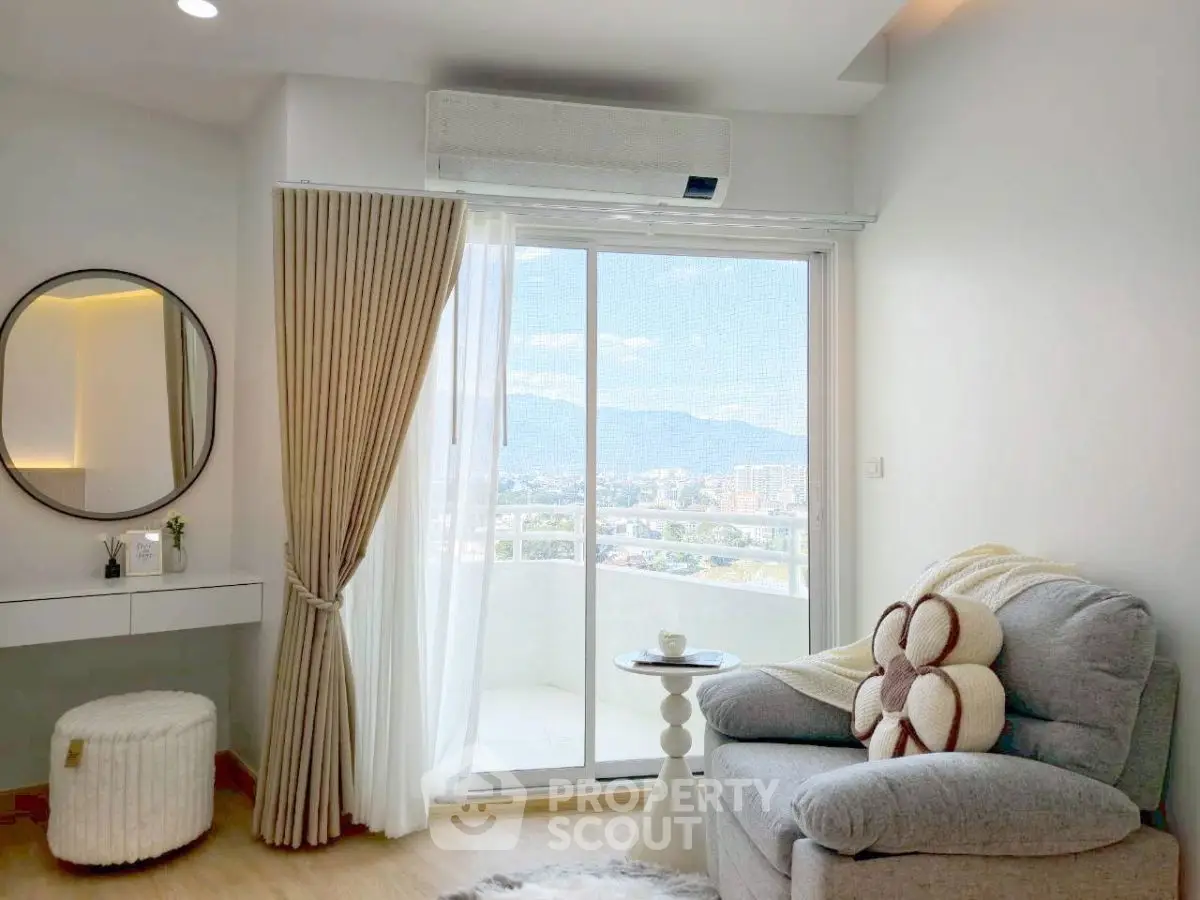Charming living room with cozy seating and balcony offering stunning city and mountain views.