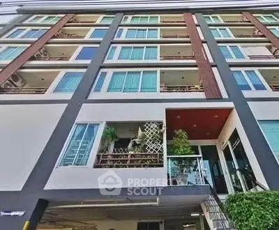 Modern multi-story residential building with balconies and large windows.