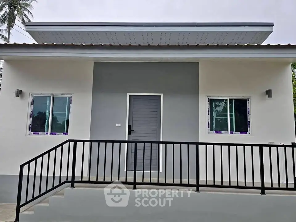 Modern minimalist single-story house with sleek facade and metal railing