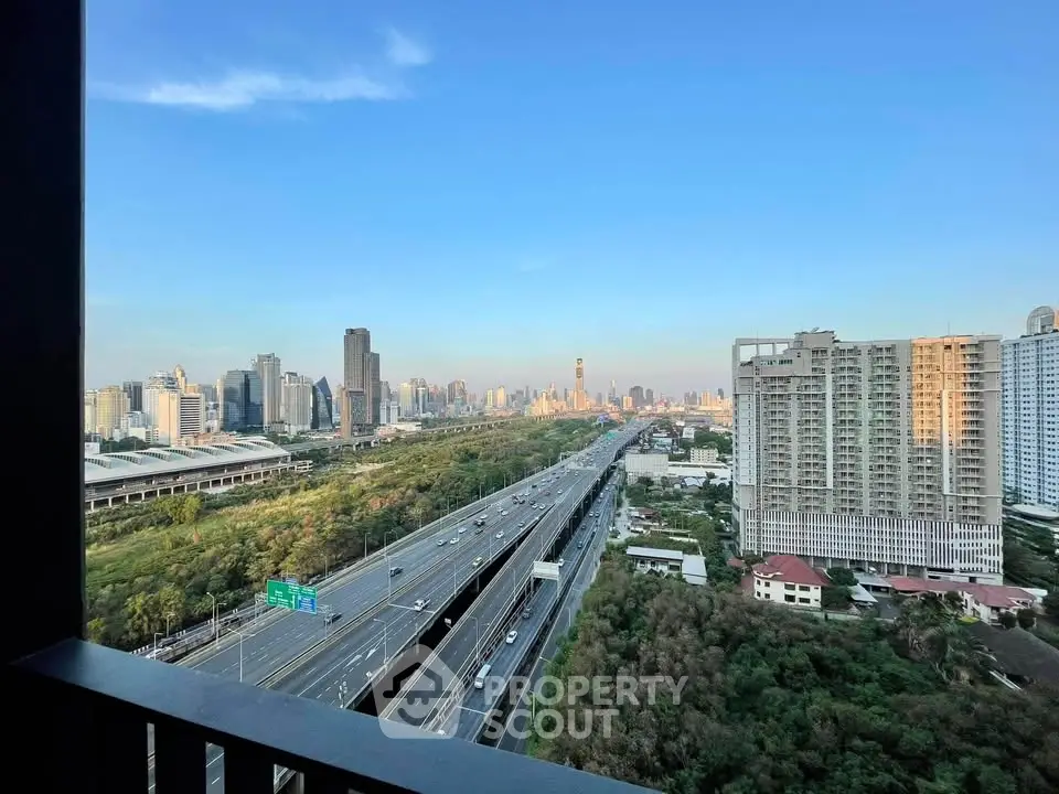 Stunning cityscape view from high-rise balcony overlooking highway and skyline.