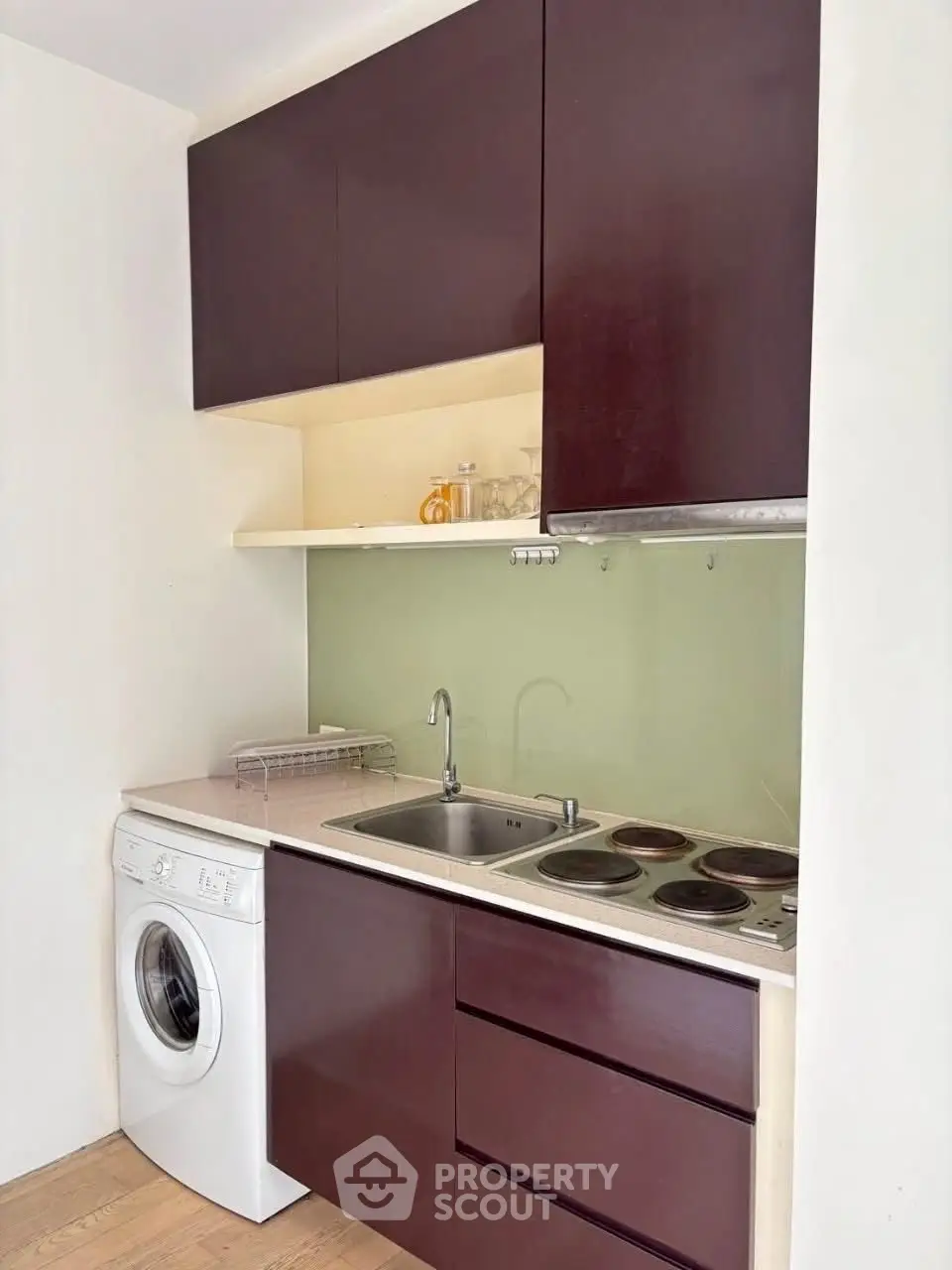 Compact modern kitchen with washing machine and electric stove in sleek design.