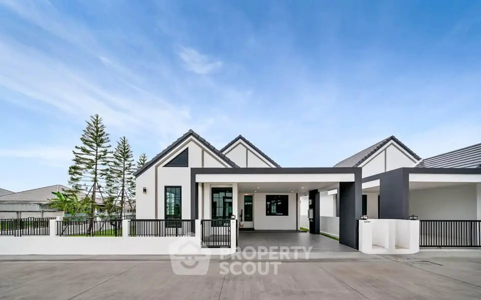 Modern single-story house with sleek design and spacious driveway under clear blue sky.