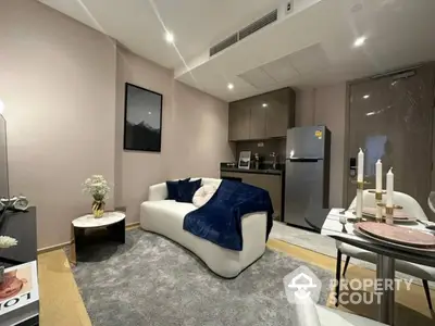 Modern living room with cozy sofa, stylish decor, and compact kitchen area in open layout apartment.