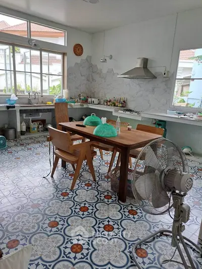 Charming kitchen with vintage tiles and wooden dining set, featuring large windows and modern appliances.