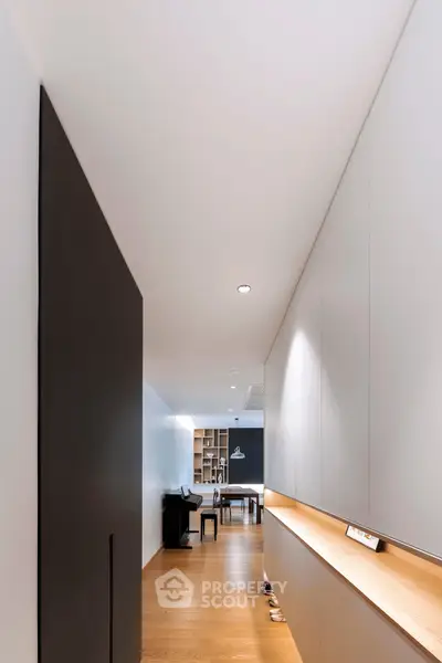 Sleek modern hallway leading to a spacious living area with wooden flooring and minimalist design.