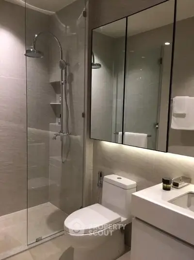 Modern bathroom with glass shower and sleek fixtures in luxury apartment.
