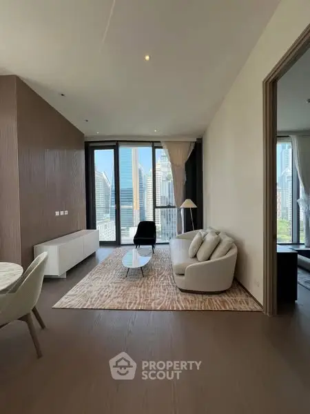 Modern living room with city view, elegant furniture, and large windows in a high-rise apartment.