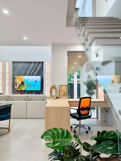 Modern living room with stylish decor and open staircase, featuring a cozy workspace and vibrant artwork.