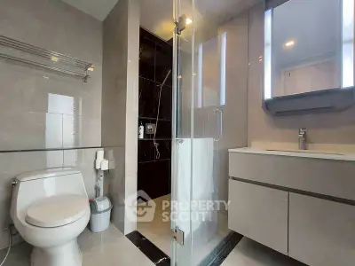 Modern bathroom with glass shower and sleek vanity in luxury apartment.
