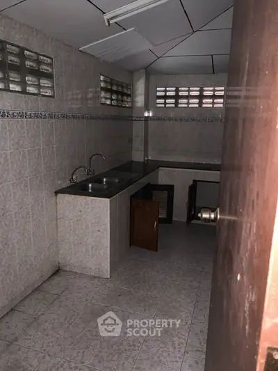 Compact kitchen space with dual sinks and tiled walls, ideal for efficient cooking.