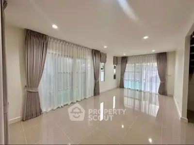 Spacious empty living room with large windows and elegant curtains