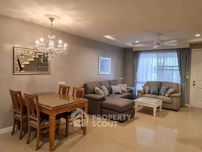 Elegant living room with chandelier, cozy seating, and dining area in modern home.