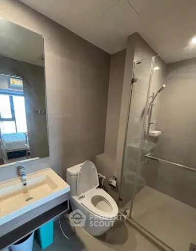 Modern bathroom with glass shower and sleek fixtures in contemporary apartment.