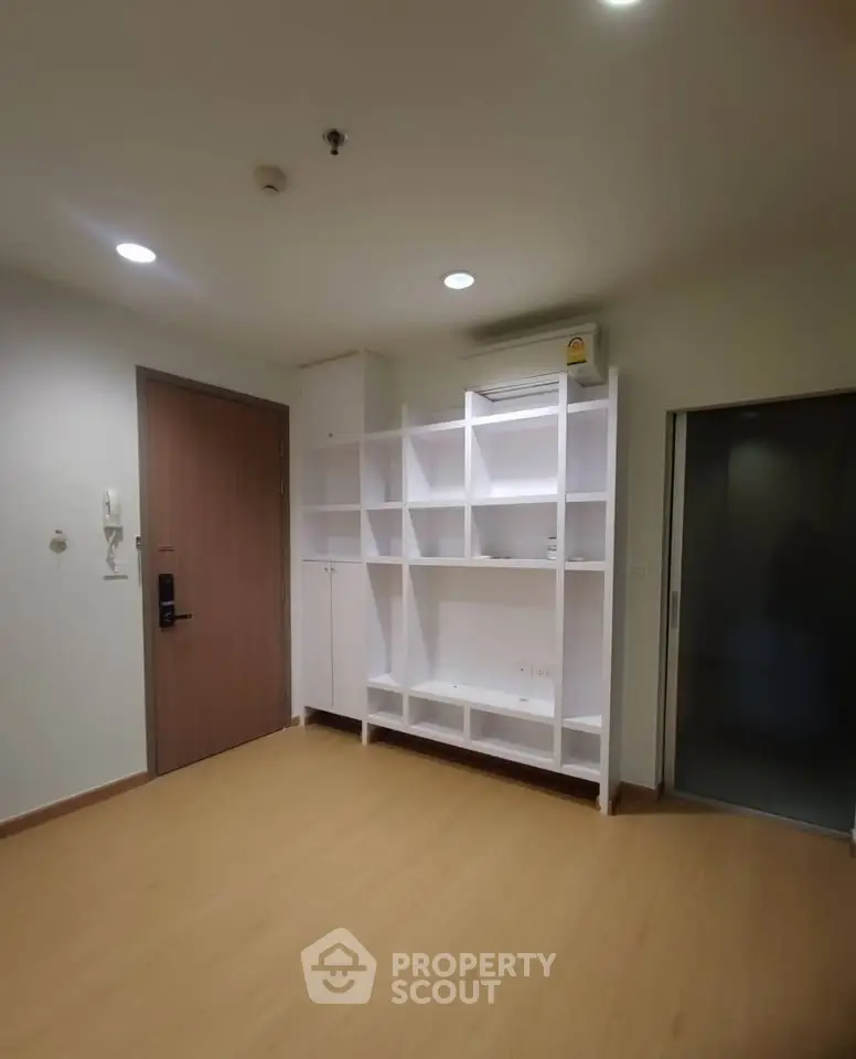Spacious modern living room with built-in white shelving and wooden flooring.