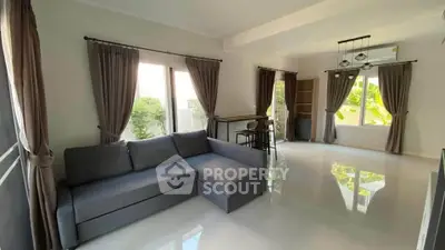 Spacious living room with modern sofa and large windows offering natural light.