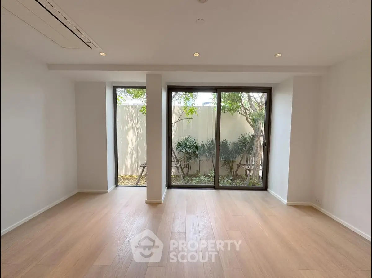 Spacious living room with large windows and garden view, perfect for natural light lovers.