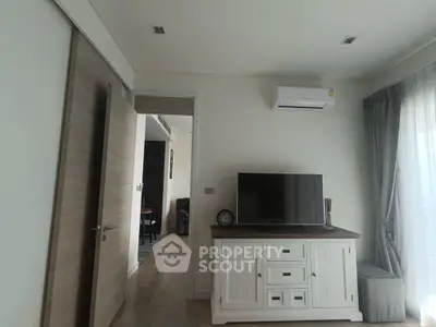 Modern living room with TV and air conditioning, featuring elegant decor and natural light.