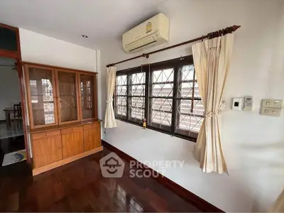 Charming living room with wooden floors, elegant curtains, and air conditioning unit.