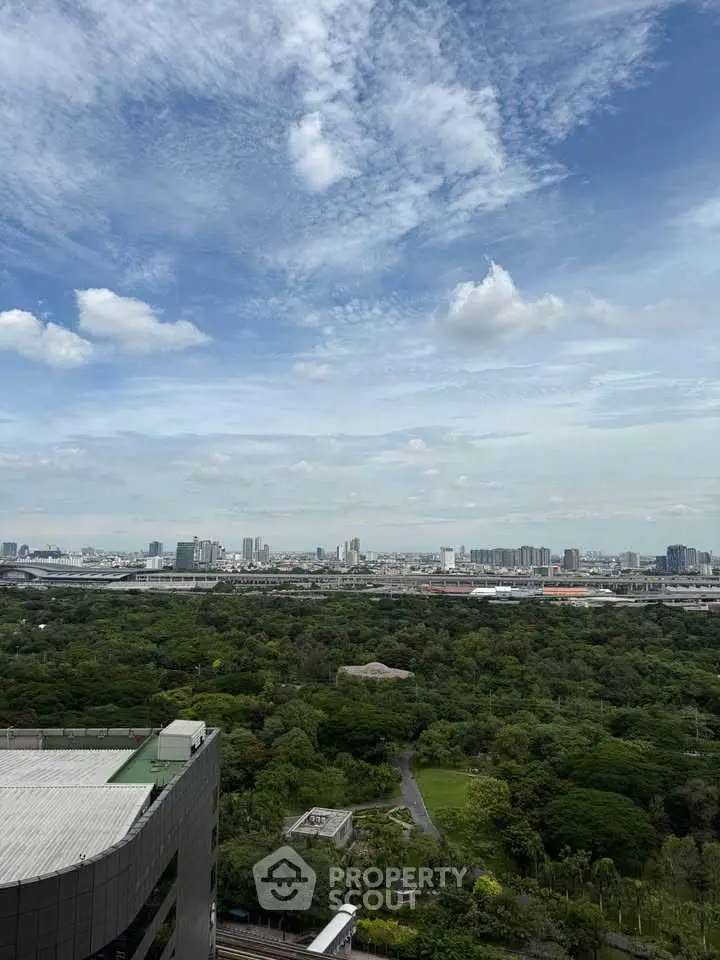 Stunning cityscape view from high-rise building overlooking lush greenery and urban skyline.
