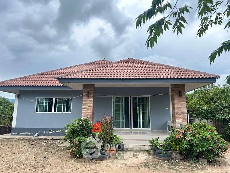 Charming single-story house with a tiled roof and lush garden, perfect for serene living.