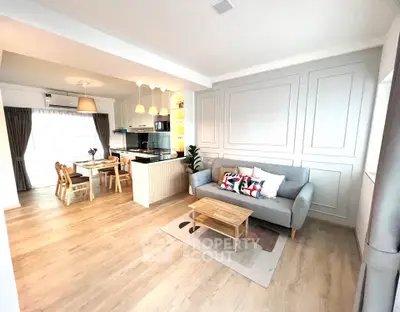 Spacious open-plan living room with modern kitchen and dining area, featuring stylish decor and ample natural light.