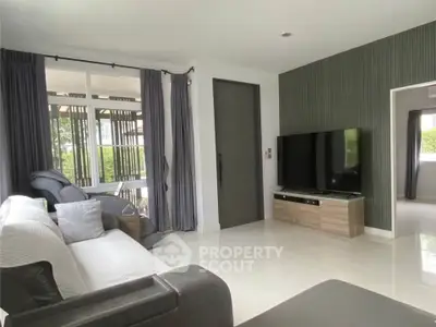 Modern living room with sleek TV setup and large windows for natural light.
