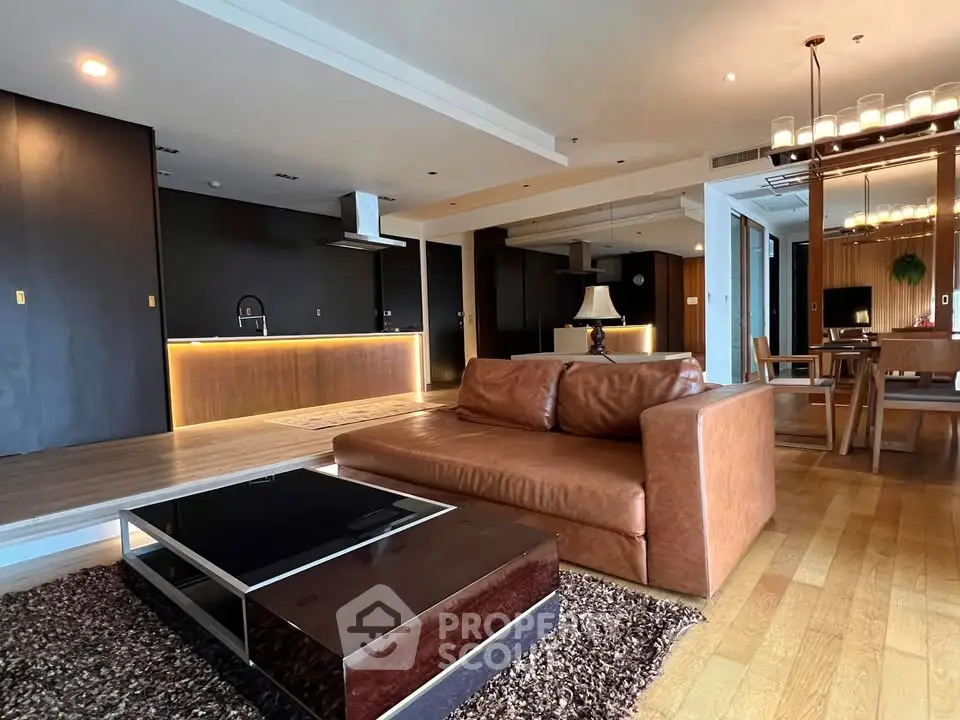 Luxurious open-plan living room with modern kitchen and elegant dining area, featuring stylish furniture and warm lighting.