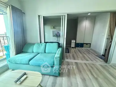 Modern living room with teal sofa and sliding glass doors leading to a cozy bedroom.