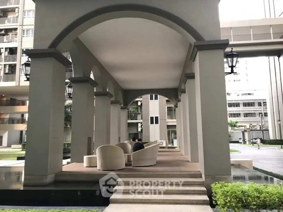 Elegant outdoor seating area in modern residential complex with arches and stylish architecture.