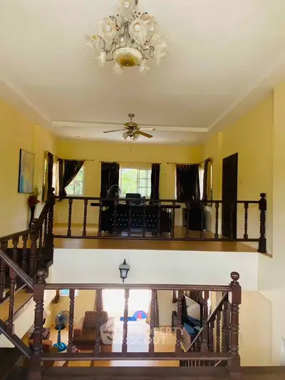 Spacious two-story living room with elegant chandelier and wooden railings