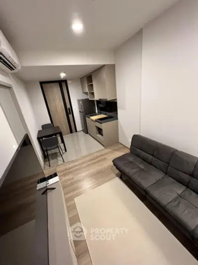 Modern compact living room with open kitchen layout and sleek furnishings.