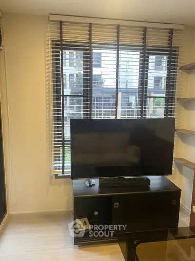 Modern living room with large TV and window blinds in a stylish apartment.