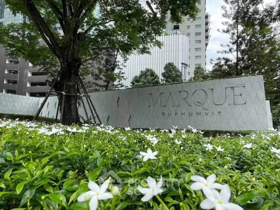 Luxurious Marque Sukhumvit entrance surrounded by lush greenery and modern architecture.