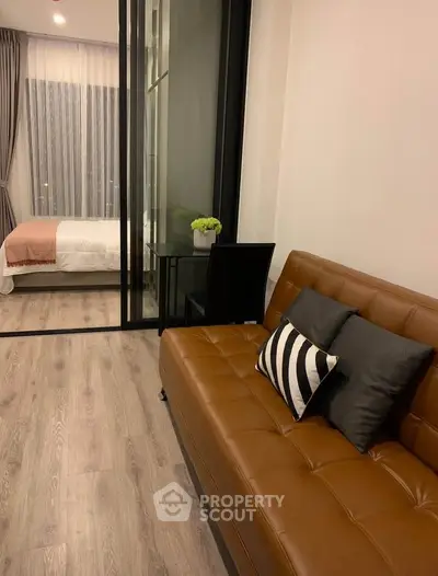 Modern apartment with stylish living room and cozy bedroom separated by glass doors.