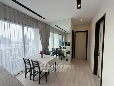 Modern living room with dining area and city view, featuring sleek design and natural light.