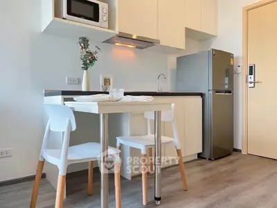 Modern kitchen with sleek cabinets, compact dining set, and stainless steel appliances in a cozy apartment.