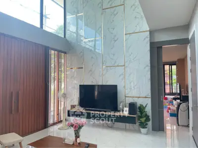 Modern living room with high ceiling, marble accent wall, and large windows for natural light.