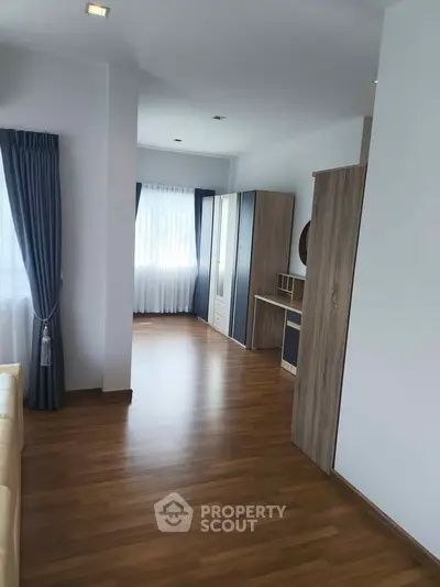 Spacious modern bedroom with wooden flooring and ample natural light.