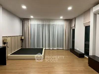 Spacious unfurnished bedroom with wooden flooring and large windows