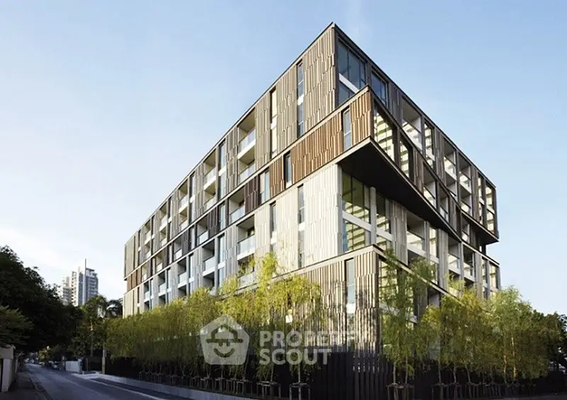 Modern architectural building with sleek design and lush greenery in urban setting.