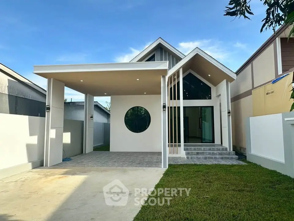 Modern single-story house with unique circular window and spacious carport, featuring a well-maintained lawn.