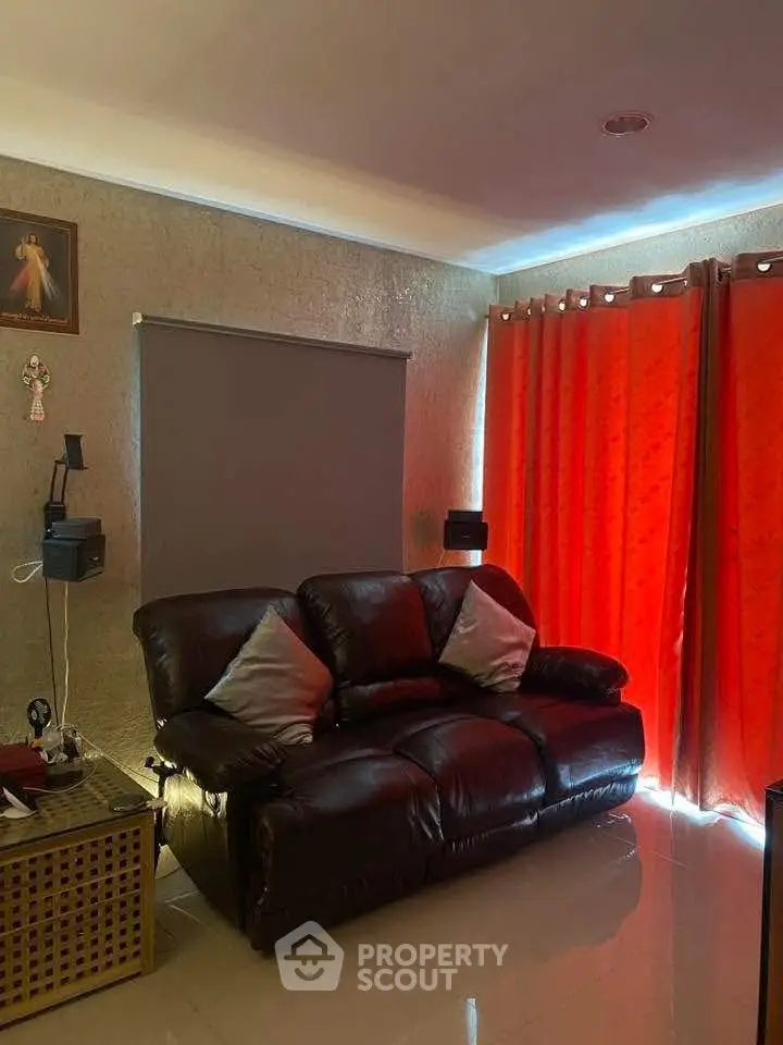 Cozy living room with leather sofa and vibrant red curtains, perfect for relaxation.