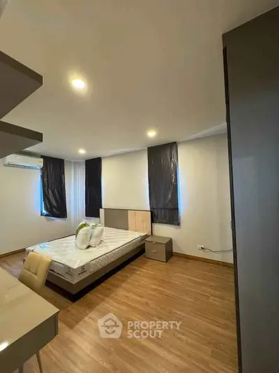 Modern bedroom with sleek design and wooden flooring, featuring a comfortable bed and ample natural light.